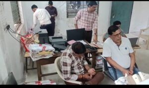 सफ़ेद शर्ट में अमीन पटवारी बिहारी सिंह व सिर झुकाये ऑपरेटर राजकुमार 